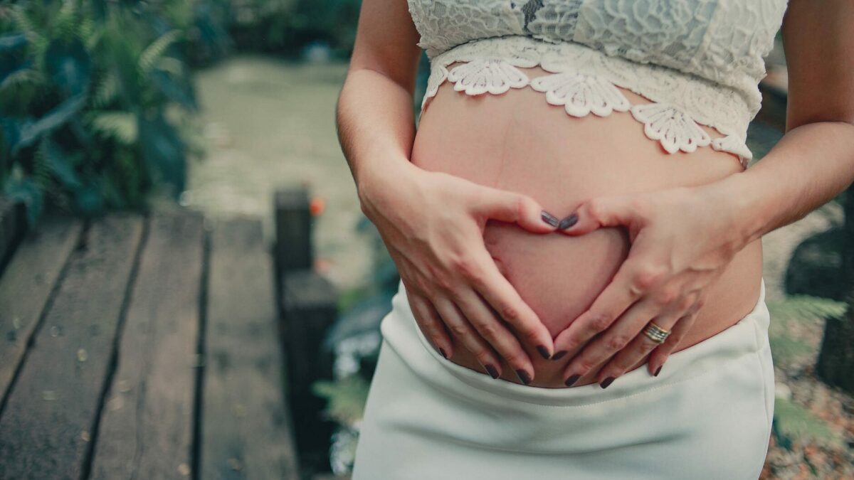 pregnant woman wearing white skirt holding her tummy